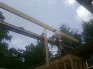 Carpenter setting a ridge beam over a new addition frame — Ice Dam Removal by Roofing Brothers in Mc Clure
