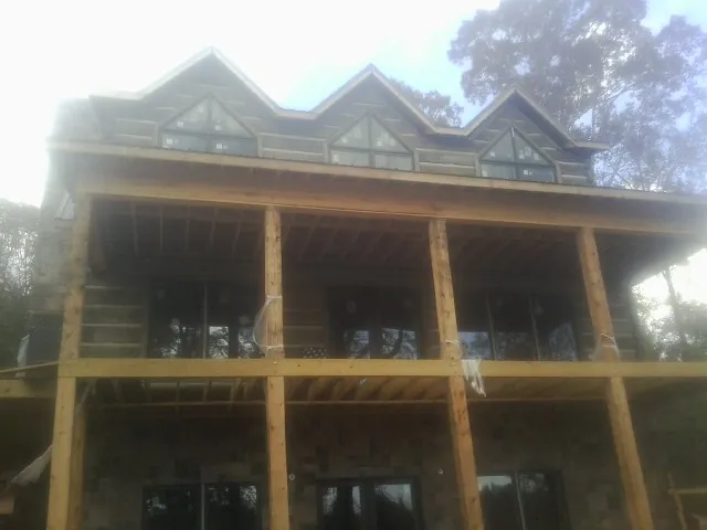 Dormers and porch framing on a large log home under construction — Roof Coating work by our crew in Mc Clure