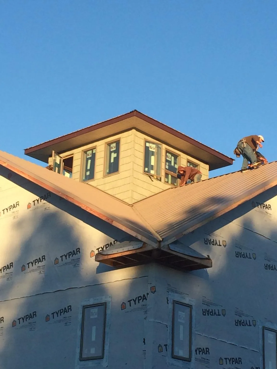 Roofers working around a rooftop cupola on a new metal roof at sunset — Roof Waterproofing in Mc Clure by Roofing Brothers